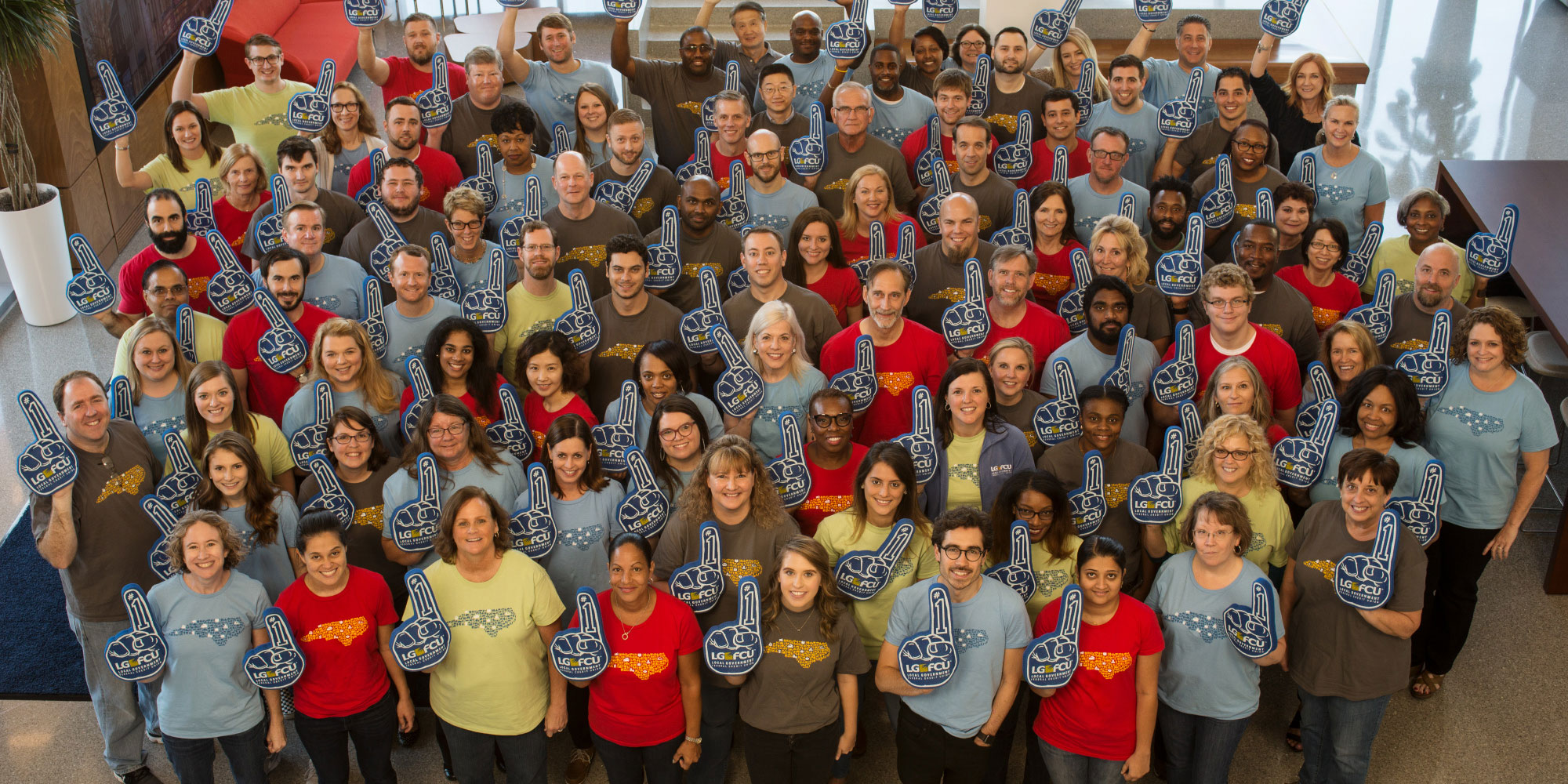 Group photo of employees holding up number one forbes hands