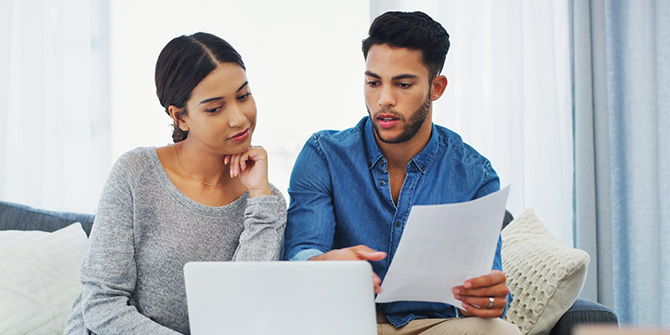 Young couple sitting on the sofa going through paperwork