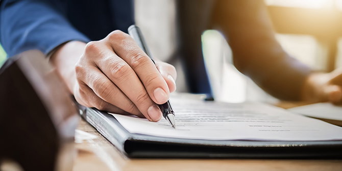 A hand signing a legal document