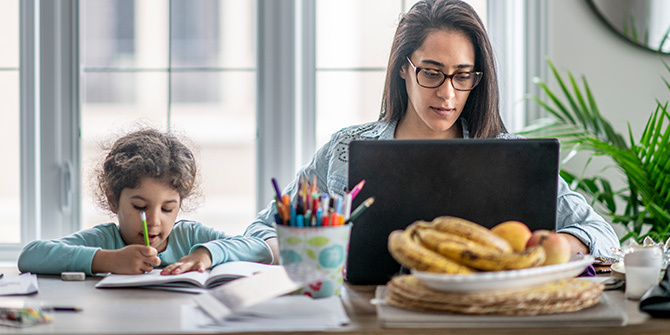 Mother works on computer while daughter works on homework