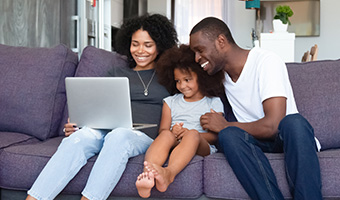 Young family using laptop together on the couch. 