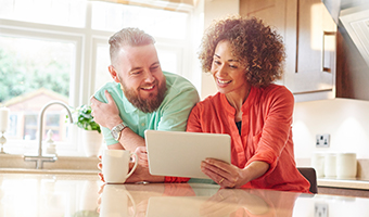 Couple at home reviews information on an electronic tablet.