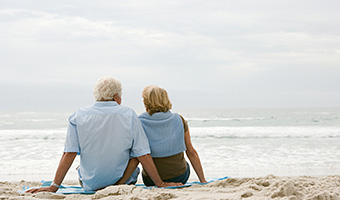 Senior couple sitting on a beach. 