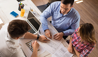 Above view of young couple signing a contract on a meeting with financial advisor.