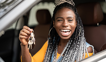 Young woman holding car keys excited about new car.