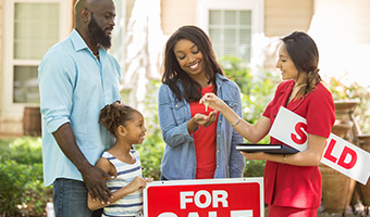 Young family receiving the keys to their new home from their realtor. 