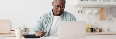 man using laptop computer, sitting in kitchen