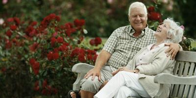 Older man and woman sitting on a bench laughing