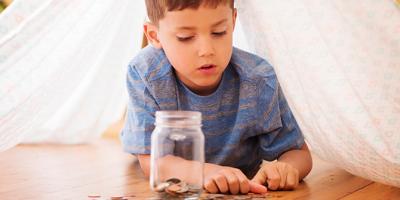Little boy counting coins to add to a jar
