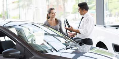 woman looking at new car with salesman