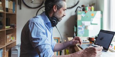 Man working on laptop and taking notes on paper