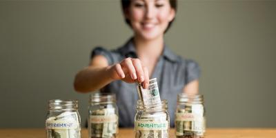 Woman putting money into a jar labeled "adventure"