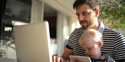 Man holding child and working on laptop
