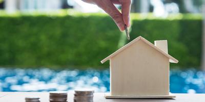 hand dropping coins in a house-shaped bank