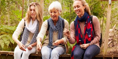 Three generations of women sitting together on a bridge