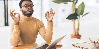 Man meditating over an open laptop