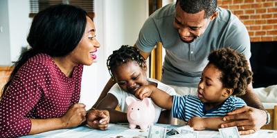 Mom and dad watch child add money to piggy bank