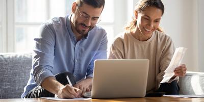 Man and woman using laptop and reviewing bills