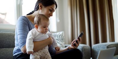 Woman holding a baby looking at her cell phone