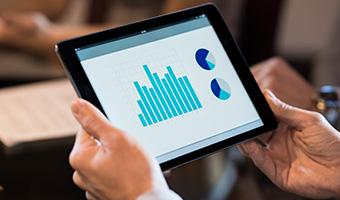 Closeup of  hands holding digital tablet and looking at a financial chart. 