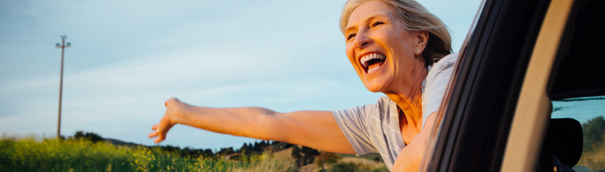 woman smiling hanging her head outside a car window