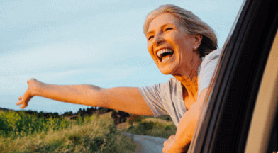 woman smiling hanging her head outside a car window