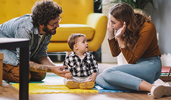 Young parents playing with toddler son in new home.