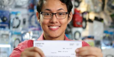 young adult holding up first paycheck