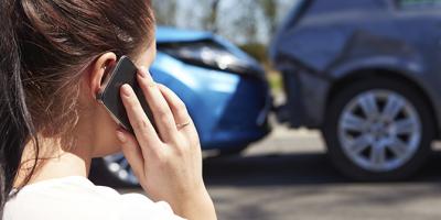 Woman holding a cellphone at the scene of a car accident