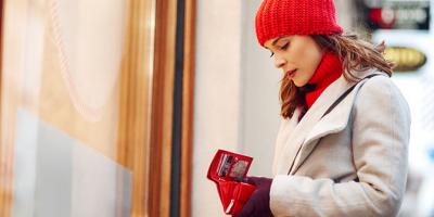 Woman standing outside store looking into wallet